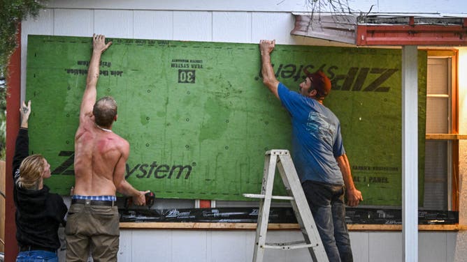 People work to secure windows with wooden panels as preparations are made for the arrival of Hurricane Helene, in Steinhatchee, Florida, on September 25, 2024. Thousands of residents on Wednesday began evacuating parts of coastal Florida as the US state braces for Hurricane Helene, forecast to barrel ashore as a powerful, potentially deadly storm. Helene strengthened into a hurricane mid-morning in the Gulf of Mexico and is "expected to bring life-threatening storm surge, damaging winds, and flooding rains to a large portion of Florida and the Southeastern United States," the National Hurricane Center in Miami said in its latest bulletin. (Photo by Miguel J. Rodriguez Carrillo / AFP) (Photo by MIGUEL J. RODRIGUEZ CARRILLO/AFP via Getty Images)