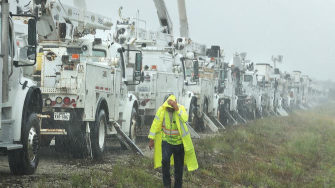 Charles Starling, a lineman with Team Fishel, is pelted with rain as he walks by a row of electrical line trucks staged in a field in The Villages, Florida, on Thursday, Sept. 26, 2024.