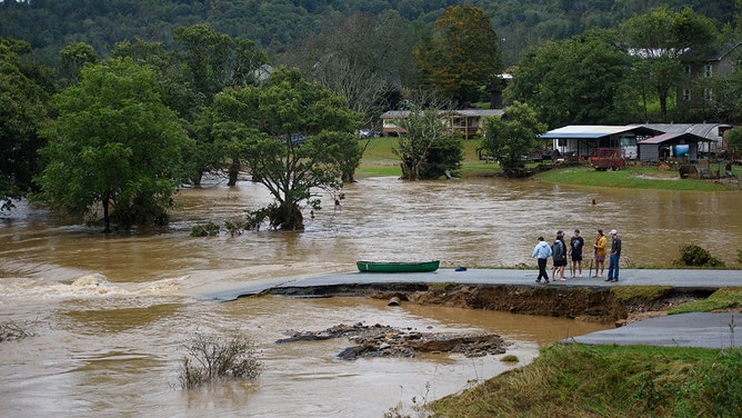 Friends talk after canoeing for 32 minutes on the flooded South Fork New River and ending up on a washed out road on September 27, 2024 in Boone, North Carolina.