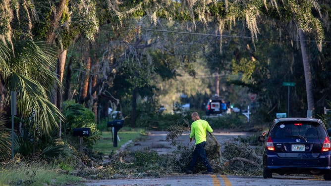 A worker clears downed limbs in Perry, FL, after Hurricane Helene passed through on Friday, September 27, 2024.