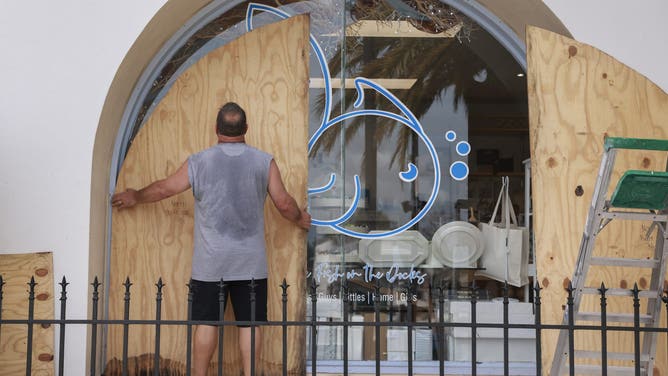 TARPON SPRINGS, FLORIDA - SEPTEMBER 25: Gary Lush places plywood against a window as he prepares his store Five FIsh ahead of the possible arrival of Hurricane Helene on September 25, 2024 in Tarpon Springs, Florida. Currently, Tropical Storm Helene is forecast to become a major hurricane, bringing the potential for deadly storm surges, flooding rain, and destructive hurricane-force winds along parts of the Florida West Coast. Helene is expected to make landfall in Florida on Thursday. (Photo by Joe Raedle/Getty Images)