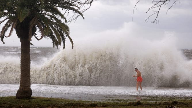 ST. PETERSBURG, FLORIDA - SEPTEMBER 26: Tanner Flynn stands in shallow water near crashing waves as Hurricane Helene passes offshore on September 26, 2024, in St. Petersburg, Florida. Helene is forecast to become a major hurricane, bringing the potential for deadly storm surges, flooding rain, and destructive hurricane-force winds along parts of the Florida West Coast. (Photo by Joe Raedle/Getty Images)