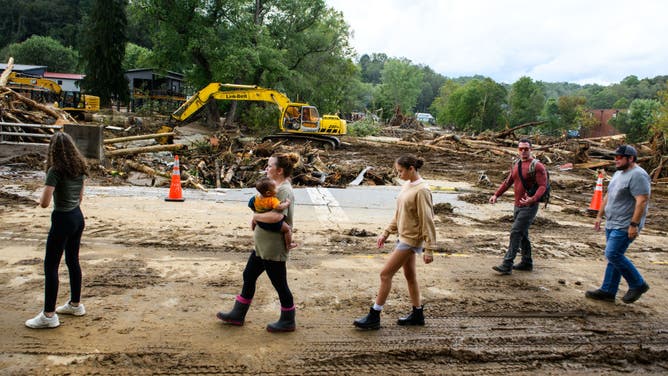 Residents walk along Catawba Avenue while debris is cleared in the aftermath of Hurricane Helene on September 29, 2024 in Old Fort, North Carolina.