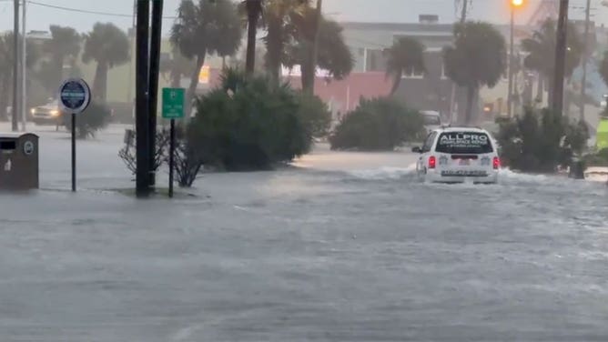 A vehicle navigates a flooded street in Carolina Beach, North Carolina, on Sept. 16, 2024, as Potential Tropical Cyclone 8 moves closer to land.