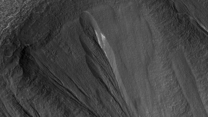 The white material seen within this Martian gully is believed to be dusty water ice. Scientists believe this kind of ice could be an excellent place to look for microbial life on Mars today. This image shows part of a region called Dao Vallis.