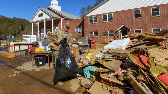 Spc. Pedro Mora-Cortes, assigned to 5th Battalion, 113th Field Artillery Regiment, carries a bag of wet garbage while helping church members and volunteers clean out a flooded church basement at Cove Creek Baptist Church in Vilas, North Carolina, Oct. 12, 2024.