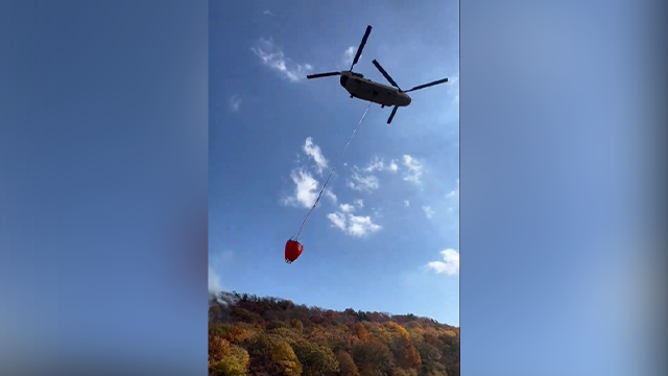 This image shows a helicopter preparing to dump water over the Hawthorne Fire in Connecticut on Wednesday, October 23, 2024.