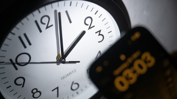 FILE- 21 March 2023, Hesse, Gießen: A smartphone displays the time "03:03", while on an analog clock it is still 02:03. On March 26, the clocks will be set forward at 02:00 to 03:00 and daylight saving time will begin. 