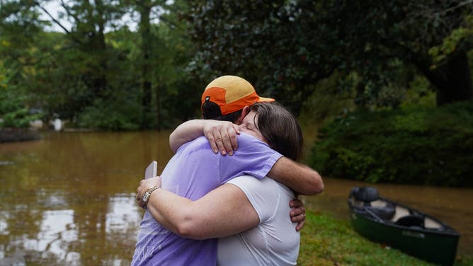 ATLANTA, GEORGIA - SEPTEMBER 27: Dan Murphy hugs his colleague after bringing his canoe to rescue them from their flooded home as the streets are flooded near Peachtree Creek after hurricane Helene brought in heavy rains overnight on September 27, 2024 in Atlanta, Georgia. Hurricane Helene made landfall late Thursday night as a category 4 hurricane in the panhandle of Florida and is working its way north, it is now considered a tropical storm. (Photo by Megan Varner/Getty Images)