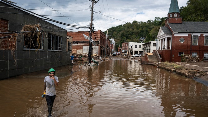 Workers, community members, and business owners clean up debris in the aftermath of Hurricane Helene in Marshall, North Carolina on Monday, Sept. 30, 2024.