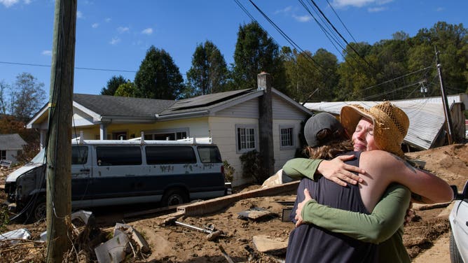 SWANNANOA, NORTH CAROLINA – OCTOBER 2: Emily Ogburn, right, hugs her boyfriend Cody Klein after he brings her a meal on October 2, 2024 in Swannanoa, North Carolina. Ogburn's home was spared and she spent the morning of the storm helping and comforting neighbors who had taken shelter on the neighbor's porch. At least 160 people have reportedly died across the southeastern United States and more than a million are without power due to the storm. The White House has approved disaster declarations in several Southern states, freeing up federal emergency management funds and resources. (Photo by Melissa Sue Gerrits/Getty Images)