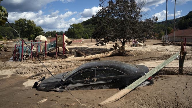 TOPSHOT - A local police car is seen half-engulfed in mud in a flooded area of ​​Lake Lure, North Carolina, October 2, 2024, following the passage of Hurricane Helene. The death toll from powerful Storm Helene, which battered the southeastern United States, has risen to at least 155, authorities said on October 1, as President Joe Biden and Vice President Kamala Harris prepared to survey the damage. (Photo by Allison Joyce / AFP) (Photo by ALLISON JOYCE/AFP via Getty Images)