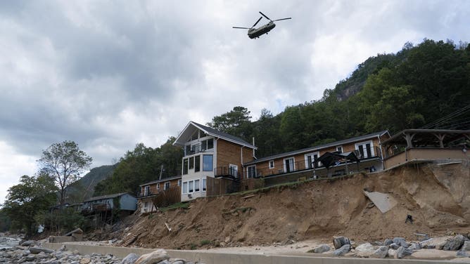 A helicopter flies over a damaged structure in downtown Chimney Rock, North Carolina, on October 2, 2024, following Hurricane Helene. The death toll from powerful Storm Helene that devastated the southeastern United States has risen to more than 155, authorities said Oct. 1, as President Joe Biden and Vice President Kamala Harris surveyed the damage. (Photo by Allison Joyce / AFP) (Photo by ALLISON JOYCE/AFP via Getty Images)