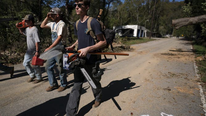 BAT CAVE, NORTH CAROLINA - OCTOBER 2: Men with chainsaws walk along Route 9 in the aftermath of Hurricane Helene on October 1, 2024 near Bat Cave, North Carolina. The death toll has topped 180 people across the southeastern U.S. due to the storm, according to published reports, which made landfall as a category 4 storm on Thursday. Millions are without power and the federal government has declared major disasters in areas of North Carolina, Florida, South Carolina, Tennessee, Georgia, Virginia and Alabama, freeing up federal emergency management money and resources for those states, according to the reports. (Photo by Sean Rayford/Getty Images)