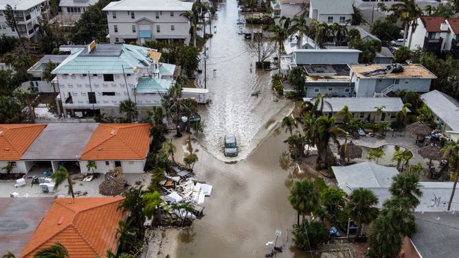 この航空写真では、2024 年 10 月 10 日にフロリダ州シエスタキーでハリケーン ミルトンの影響で浸水した道路を走行する車が写っています。