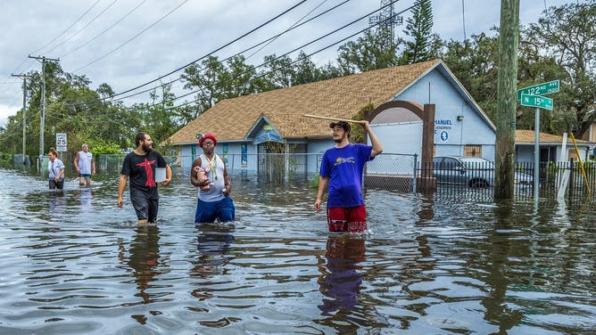 Residents walk through a flooded street in North Tampa on Thursday, Oct. 10, 2024, a day after Hurricane Milton crossed Florida's Gulf Coast. (Pedro Portal/Miami Herald/Tribune News Service via Getty Images)