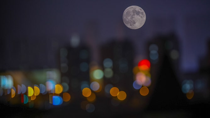 The full Hunter's Moon rises in the night sky over buildings on October 16, 2024 in Huaibei, Anhui Province of China.