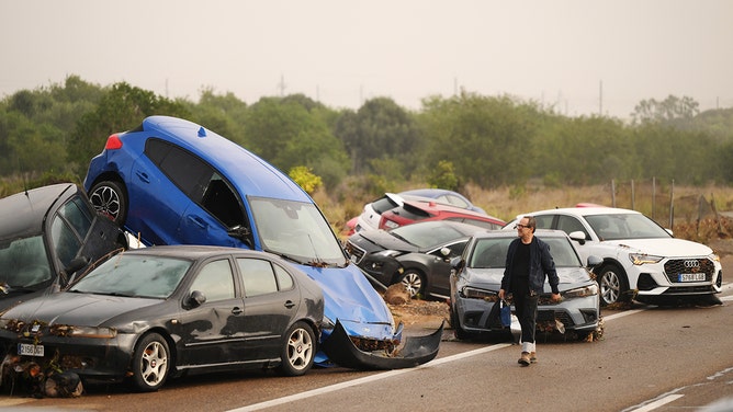 A man walks past piled up cars after flash flooding hit the region overnight on October 30, 2024 in Valencia, Spain.