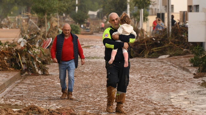 An emergency worker carries a child after a flash flood hit the region on October 30, 2024 in Valencia, Spain.