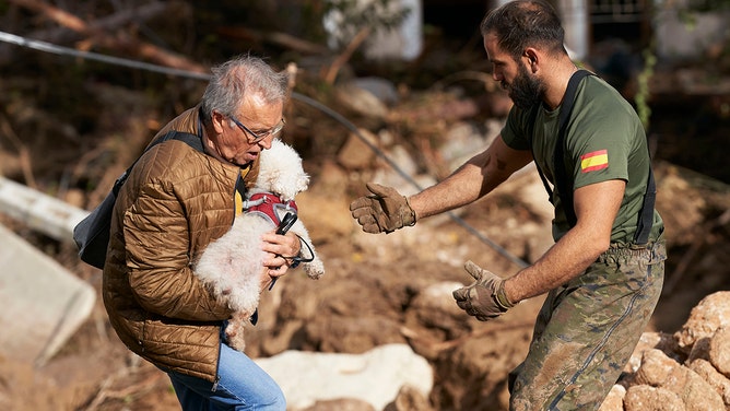 A man carries a dog after flash floods hit the region on October 30, 2024 in Letur, Albacete province, Spain.