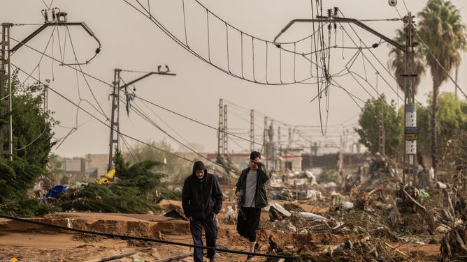 VALENCIA, SPAIN - OCTOBER 30: Men walk along train tracks covered debris after flash-flooding hit the region on October 30, 2024 in Valencia, Spain. Spanish authorities said on Wednesday that at least 52 people had died in the Valencia region overnight after flash-flooding followed heavy rain. Spain's meteorological agency had issued its highest alert for the region due to extreme rainfall.