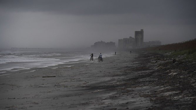 People bike on the beach ahead of hurricane Matthew in Atlantic Beach, Florida, on October 5, 2016.