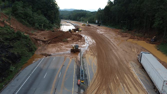 作業員が州間高速道路から泥や瓦礫の撤去を始めた後の地滑り現場の航空写真。