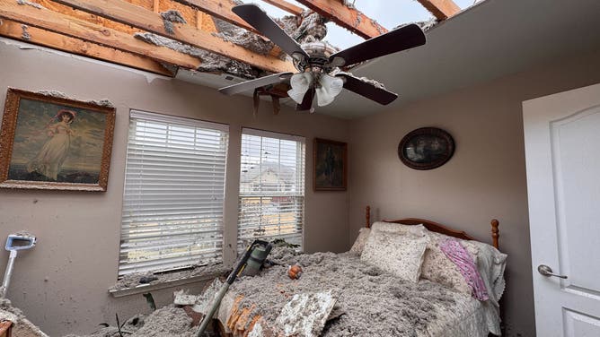 Debris litters a bedroom after the roof was ripped off of a home during storms.