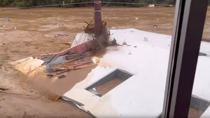 A wall gets cut in half by a power pole during flooding on the French Broad River in Asheville on Sept. 27, 2024.