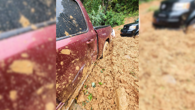 Keys's red truck, with her friend's black vehicle in tow, surrounded by mud.