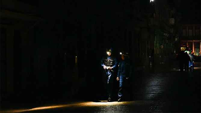 Rescue workers walk on a darkened street due to a blackout after the pass of hurricane Rafael in Havana, on November 6, 2024. Hurricane Rafael left Cuba on Wednesday night, leaving the island in darkness with widespread power outages and destruction in some villages after hitting as a powerful Category 3 hurricane. (Photo by Yamil LAGE / AFP) (Photo by YAMIL LAGE/AFP via Getty Images)