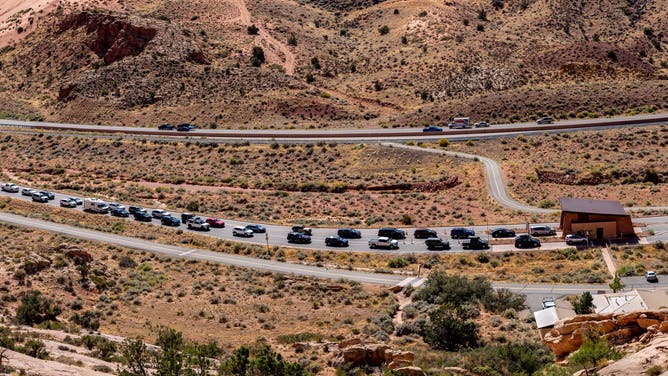 ARCHES NATIONAL PARK, UT - OCTOBER 3: Despite a timed-entry, cars line up at the entrance to Arches National Park on October 3, 2023 near Moab, Utah. Arches National Park, one of the Fabulous Five Utah Parks, is located in southeastern Utah near the town of Moab. The park preserves a colorful eroded landscape of numerous canyons, mesas, balancing rocks, and buttes, along with nearly 2,000 natural sandstone arches. 