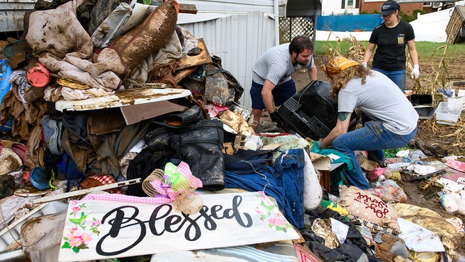 Guy Thomas, Ryan Creel, and Brittany Heathman, students at Western North Carolina Univerity remove damaged items from a home off Broad Street on October 4, 2024 in Clyde, North Carolina.