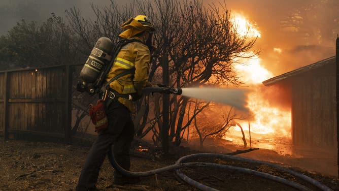 A firefighter attempts to control the blaze burning a structure as the Santa Ana wind-fed Mountain fire scorches acres, in Camarillo, California, on November 6, 2024.
