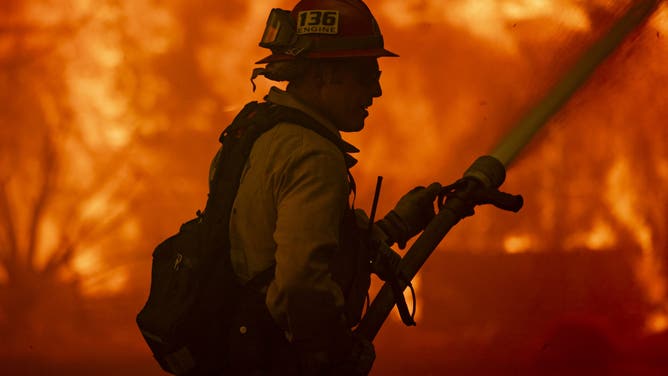 A firefighter attempts to control the blaze burning a house as the Santa Ana wind-fed Mountain fire scorches acres, in Camarillo, California, on November 6, 2024.