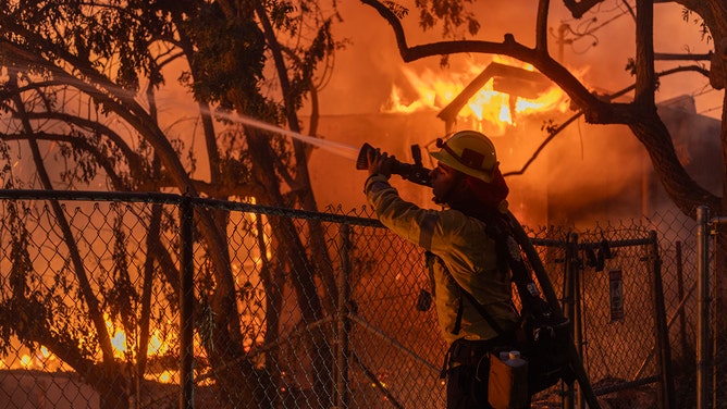 A Los Angeles County firefighter battles flames as a house burns from the Mountain Fire on November 6, 2024 in Camarillo, California.