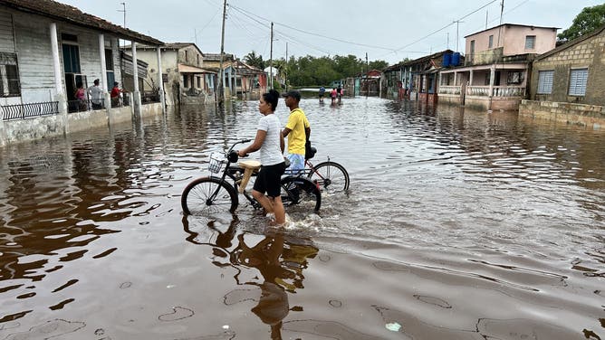 トップショット – 2024年11月7日、キューバのマヤベケ州バタバノでハリケーン・ラフェル通過後、浸水した通りを歩く人々。ハリケーン・ラファエルは水曜日、キューバ全土で停電を起こし、最近の停電と過去の致命的な嵐で未だに動揺している資金難の島を直撃した。ラファエルは人口1000万人のカリブ海の島に上陸したとき、カテゴリー3の大型ハリケーンに勢力を強めた。 (写真提供：ヤミル・ラージ/AFP) (写真提供：ヤミル・ラージ/AFP、ゲッティイメージズ経由)