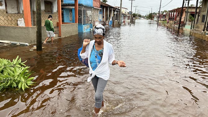 2024年11月7日、キューバのマヤベケ州バタバノでハリケーン・ラフェル通過後、浸水した通りを歩く人々。最近の停電と以前の致命的な嵐から回復しています。ラファエルは人口1000万人のカリブ海の島に上陸したとき、カテゴリー3の大型ハリケーンに勢力を強めた。 (写真提供：ヤミル・ラージ/AFP) (写真提供：ヤミル・ラージ/AFP、ゲッティイメージズ経由)