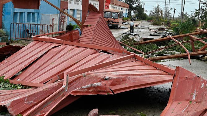 A resident stands amid debris and fallen trees after Hurricane Rafael passed through Artemisa, Cuba, on November 7, 2024. Cubans were assessing damage caused by Hurricane Rafael, which hit the island on Thursday and plunged it into darkness but caused no reported deaths. so far. 