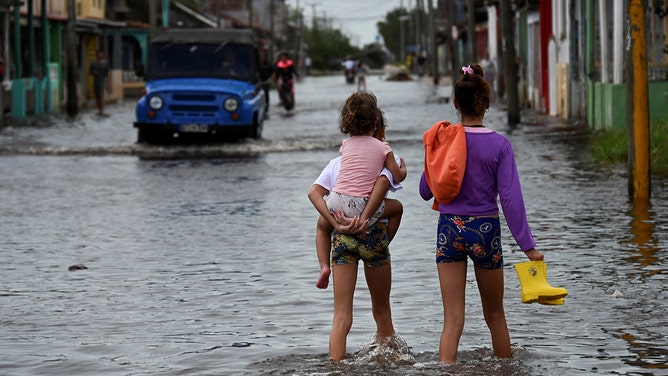 Children walk through flooded waters after the passage of Hurricane Rafael in Batabano, Artemisa province, Cuba, on November 7, 2024.