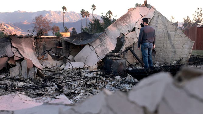 Brandon Francis salvages through his grandmothers house after it burned to the ground from the Mountain Fire in Camarillo.