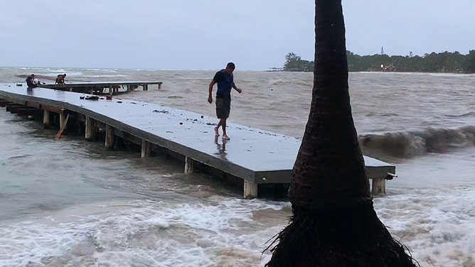 A man walks on a wharf ahead of the arrival of Tropical Storm Sara in West Bay, Roatan, Honduras on November 14, 2024.