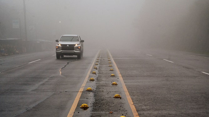 A car drives through heavy fog ahead of the arrival of Tropical Storm Sara in Siguatepeque, Honduras on November 14, 2024.
