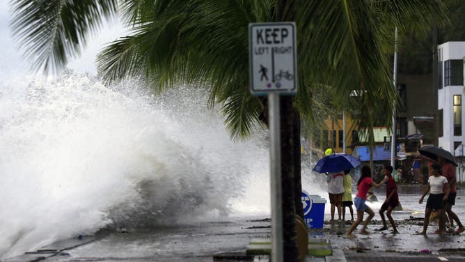 TOPSHOT - People (R) react as large waves break along a seawall ahead of the expected landfall of Super Typhoon Man-yi, in Legaspi City, Albay province on November 16, 2024.