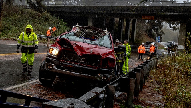 Workers remove a mangled car after a collision between a downed tree and a vehicle amidst the ongoing atmospheric river event in Loleta, Calif., Wednesday, Nov. 20, 2024.