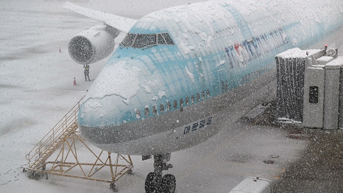 2024年11月27日、ソウル西部の仁川国際空港で、降雪の中、滑走路に駐機している大韓航空の飛行機を点検する作業員が窓から見た。