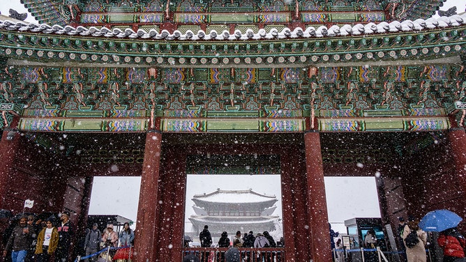 People visit the Gyeongbokgung Palace amid heavy snowfall in central Seoul on November 27, 2024.