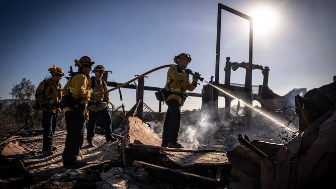 Firefighters amid charred remains of a home burned by the Mountain Fire in California.