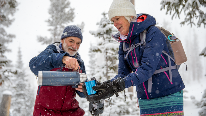 A man and woman on a snowy hike.