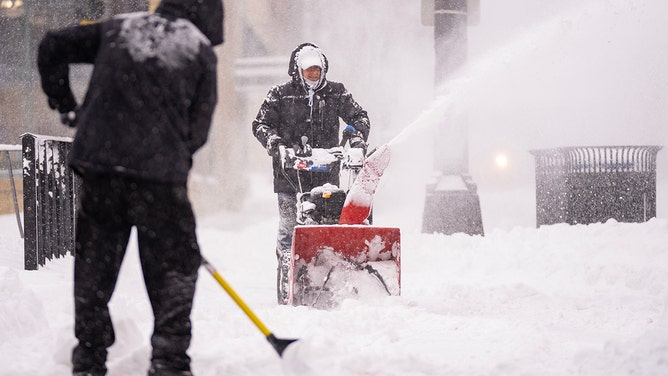 Luis Cabrera and Carlos Toro, left to right, clear snow on the sidewalk in front of the Butchers Tale Thursday, Feb. 23, 2023 in downtown Minneapolis, Minn.
